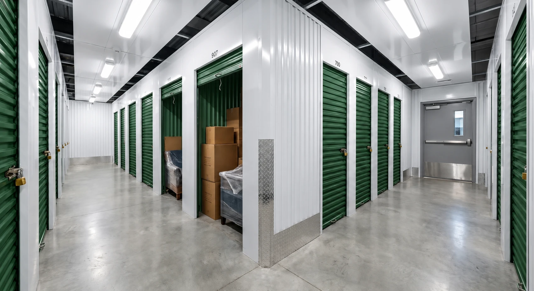 Photographie réelle d'un intérieur de garde-meubles ou facility de self-stockage professionnel : rangées de boxes métalliques individuels bien organisés, éclairage moderne, allées propres et spacieuses, porte d'accès visible, impression générale de sécurité, propreté et organisation. Ou alternativement : client satisfait ouvrant la porte de son box personnel dans un espace de stockage climatisé et sécurisé, montrant la facilité d'accès et la qualité des installations.
